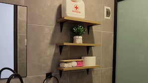 Une salle de bain moderne équipée de toilettes, d’un lavabo et d’une étagère où sont rangés les articles de toilette.
