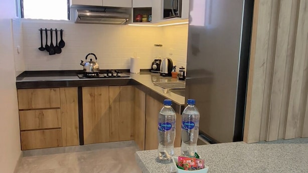 Une cuisine moderne avec des meubles en bois, un réfrigérateur en acier inoxydable et un plan de travail en granit.