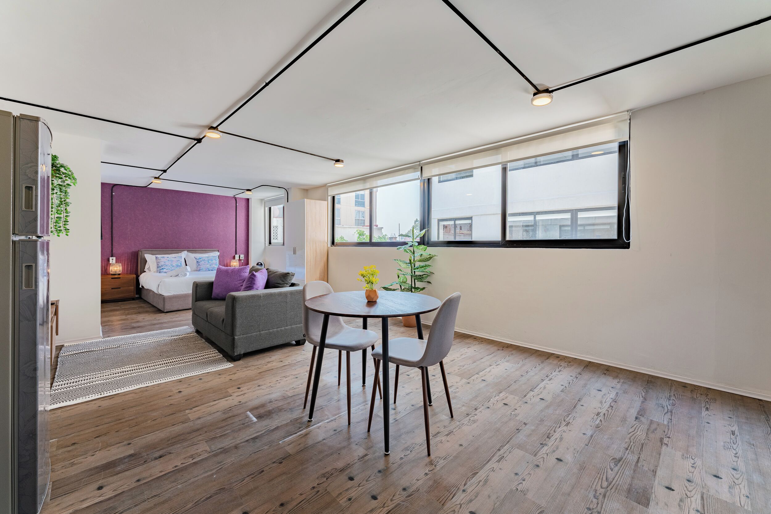 Un apartament modern amb zona de menjador, saló i dormitori.