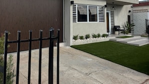 Une maison moderne à deux étages, dotée d’un garage, d’une cour avant avec une pelouse et d’un portail en métal noir.