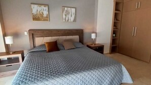 Ein Schlafzimmer mit einem großen Bett, zwei Nachttischen, einem Kleiderschrank und zwei Wandbildern.