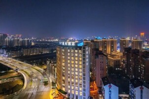 Un hotel de varios pisos con un letrero llamativo, rodeado de edificios altos y una calle bien iluminada.