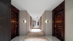 A long, narrow hallway with dark wooden doors on either side, a marble floor, and recessed lighting. - Guangsha Hotel (Shengzhou)