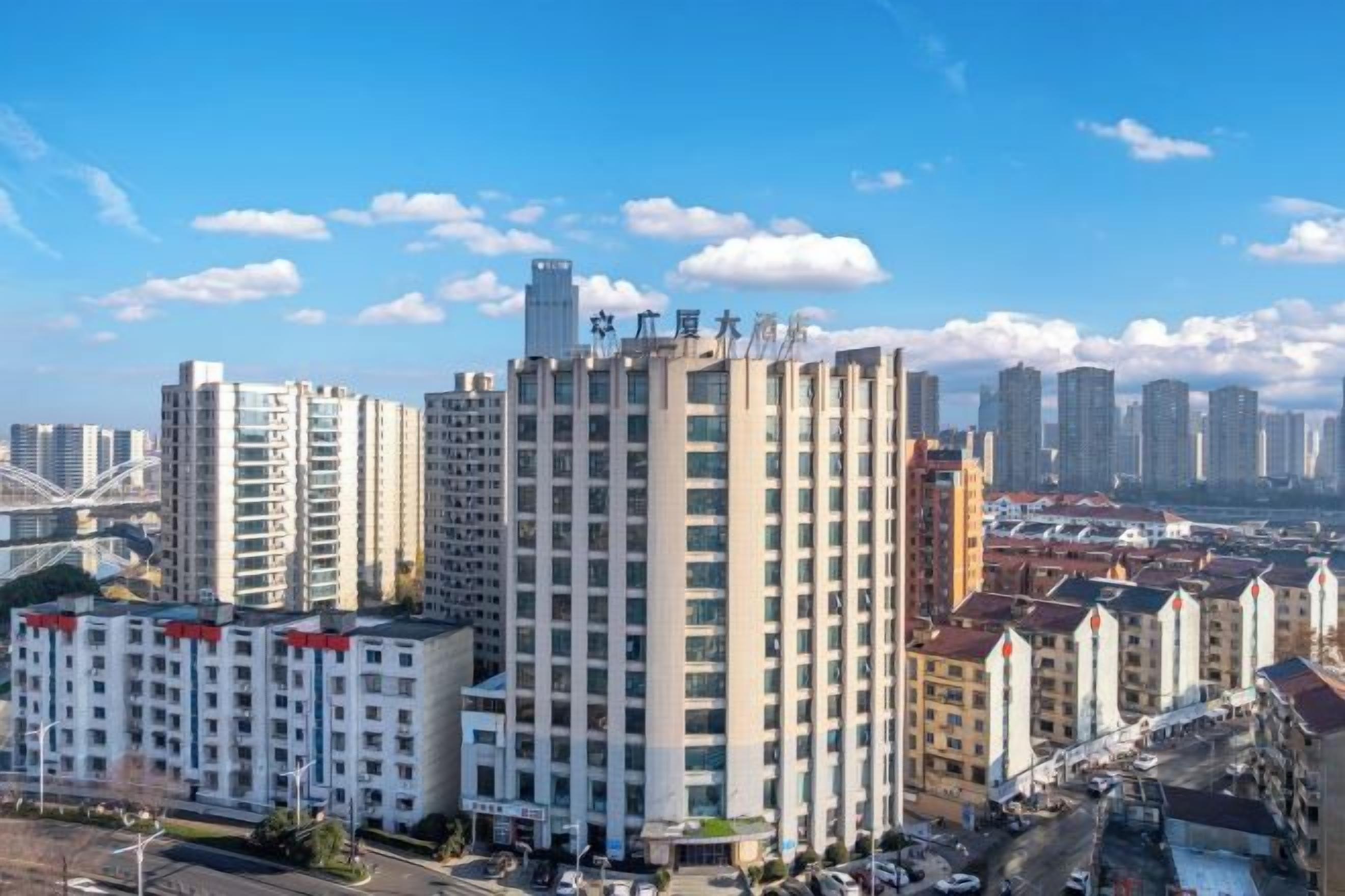 A high-rise building with multiple floors, surrounded by other buildings, under a clear sky.