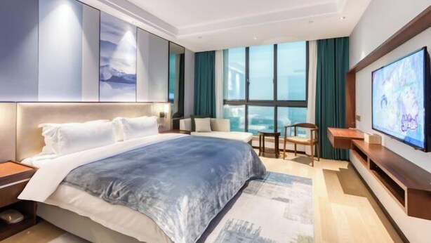 A modern hotel room with a large bed, a television, a seating area, and a large window. - Guangsha Hotel (Shengzhou)