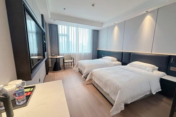 A hotel room with two beds, a desk, a chair, and a window with curtains. - Guangsha Hotel (Shengzhou)