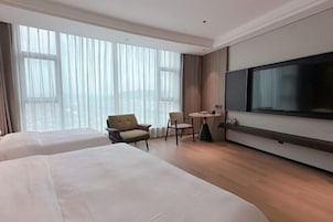 Una habitación de hotel con dos camas, un televisor, una mesita y una silla.