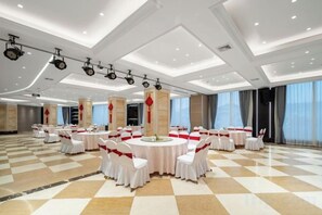 A large conference room with multiple round tables, white chairs, and red accents. - Guangsha Hotel (Shengzhou)
