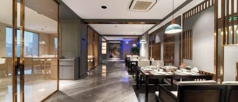 A modern hotel lobby with a long reception desk, seating area, and glass partitions.
