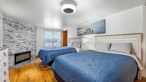 Une chambre avec deux lits, une cheminée et un tableau représentant un paysage urbain.