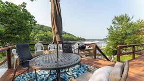 Une terrasse avec une table ronde en métal, des chaises en plastique blanc et un tapis à motifs.