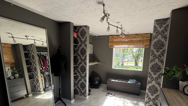 Een ruime kamer met een grote spiegel, een kledingkast en een zithoek met een bank.