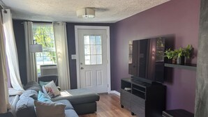 Een moderne woonkamer met een hoekbank, een flatscreen televisie en een houten vloer.