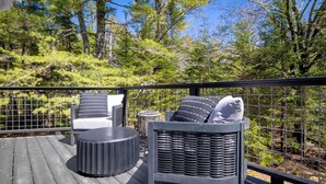 Una terraza con mobiliario exterior, incluyendo una silla y una mesa, rodeada por una barandilla metálica.
