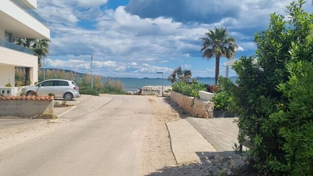 A coastal road leading to a building with a car parked in front.