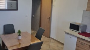 A compact kitchen with a microwave, a small refrigerator, and a dining table with chairs.