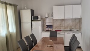 Una cocina compacta con armarios blancos, un microondas y un lavamanos.