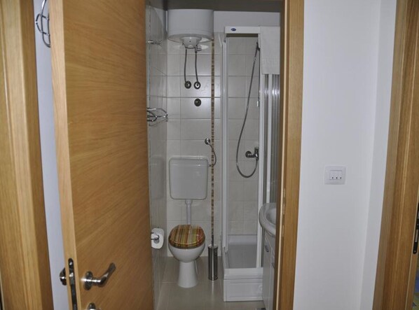A small bathroom with a toilet, a shower, and a sink.