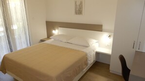 A neatly made bed with a beige bedspread, a white pillow, and a headboard with wall-mounted lights.