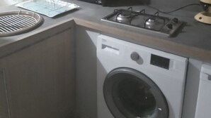 A compact kitchen with a washing machine, a microwave, and a gas stove. - Studio center var circuit loan (Le Luc)