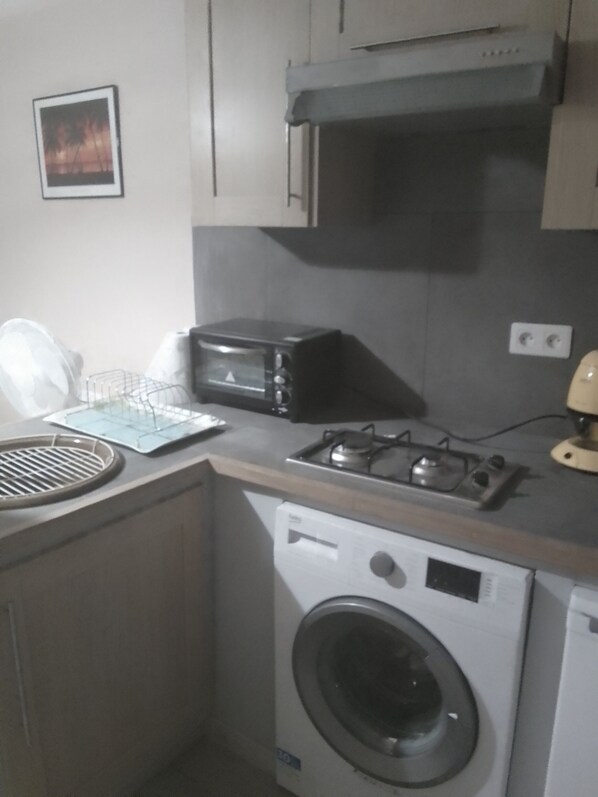 Una cocina compacta equipada con lavadora, microondas y cocina a gas.