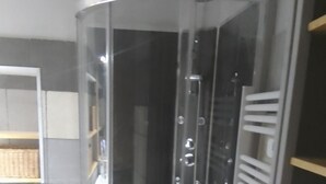 A corner shower enclosure with a glass door, a handheld showerhead, and a wall-mounted towel rack. - Studio center var circuit loan (Le Luc)