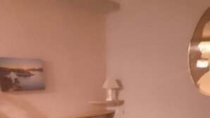 A cozy room with a beige sofa, a white pillow, a small table with a lamp, and a painting on the wall. - Studio center var circuit loan (Le Luc)