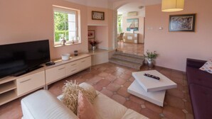 A living room with a television, sofa, coffee table, and a staircase leading to a dining area.