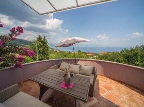 A balcony with a table, a chair, and an umbrella.