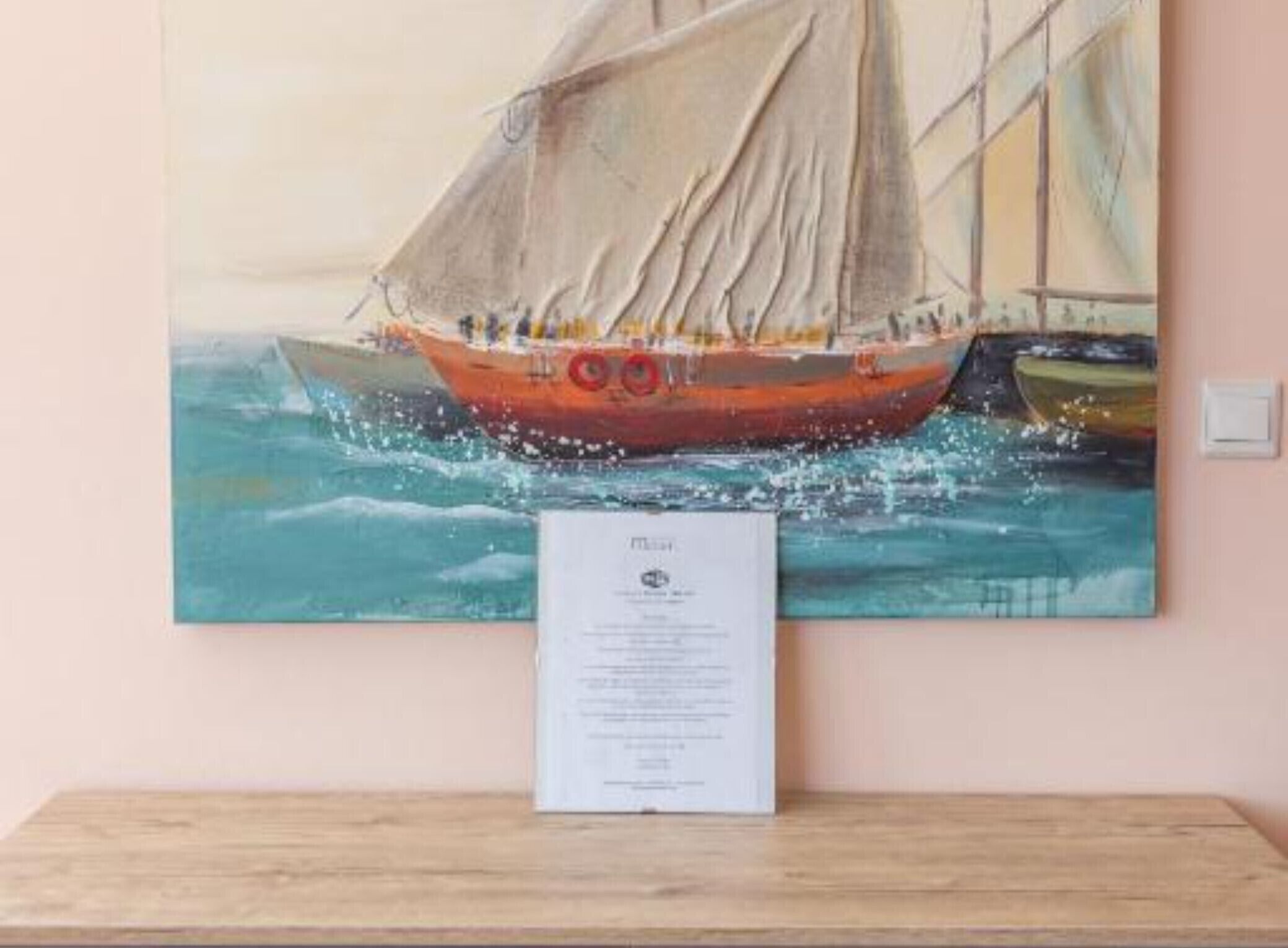 A painting of a sailboat on water with a plaque in front.