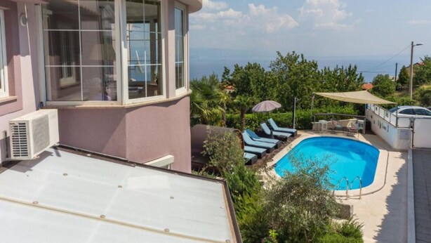 Zona de piscina con sillones de descanso y vista al mar.