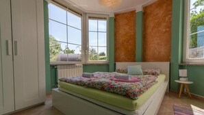 Un dormitorio con cama, ventana, radiador y armario.