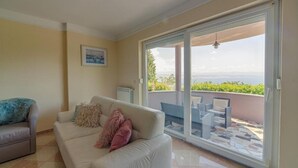 Una sala de estar con un sofá color beige, una mesita y vistas a un balcón con mobiliario exterior.