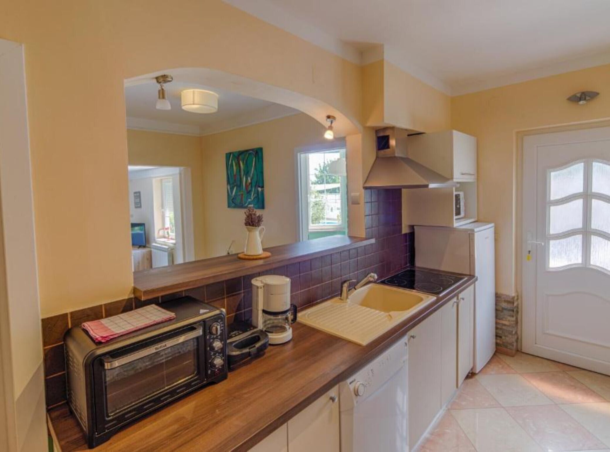 A compact kitchen with a toaster, coffee maker, and a microwave. There is a window with a view of greenery outside.