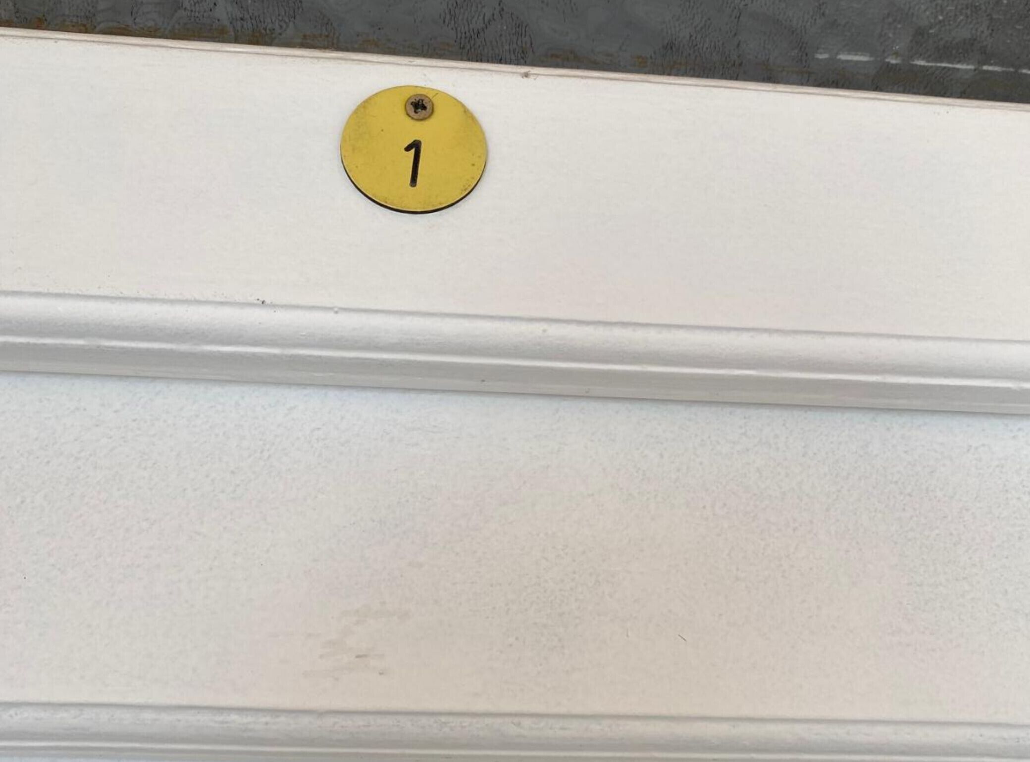 Eine weiße Wand mit einer gelben Türschild mit der Nummer 1.