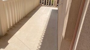 A corridor with tiled flooring and a series of vertical columns on one side.