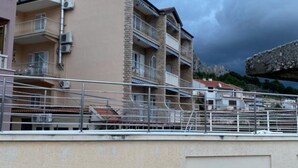 A multi-story building with balconies, air conditioning units, and a metal railing in front.