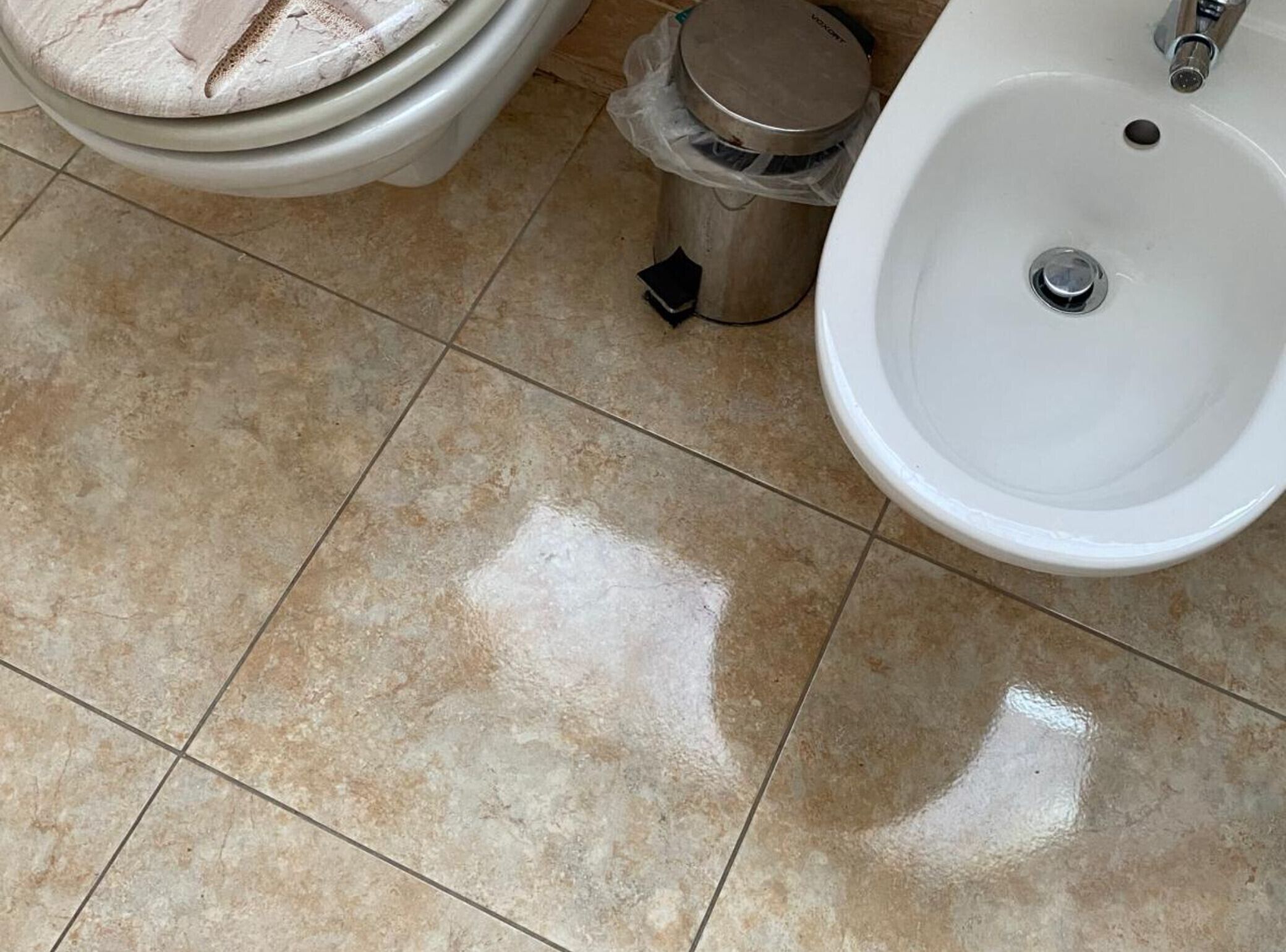 A bathroom with a toilet, bidet, and trash bin.