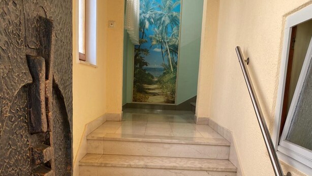 Una escalera con un cuadro que muestra palmeras y una playa en la pared.