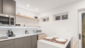 A modern kitchen with a microwave, coffee maker, and a small dining area with a table and chairs. - Dog-Friendly Apt w/ EV Charger / Walk to Aspen (Aspen)