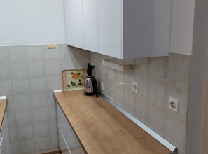 A kitchen with a wooden countertop, a kettle, and a flower-patterned tray.