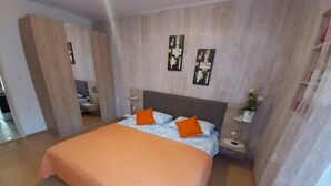 A bedroom with a large bed, a nightstand, a mirror, and a wall-mounted artwork. - Apartments Ivan Supetar - Two Bedroom Apartment with Terrace no.1 (Supetar)