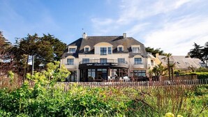 A large, two-story building with a curved facade, a sign reading "Castel Noir," and a patio area with outdoor seating. - Hotel Castel Moor (Le Croisic)