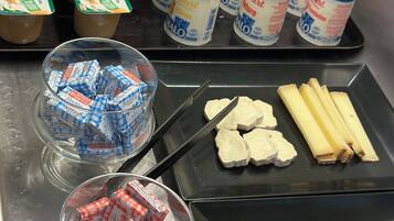 Un comptoir de cuisine sur lequel on trouve divers aliments, notamment un panier d’oranges, des pots de yaourt, des collations emballées et des tranches de viande.