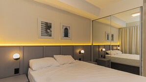 A hotel room with a large bed, bedside tables, wall-mounted lights, and framed pictures.