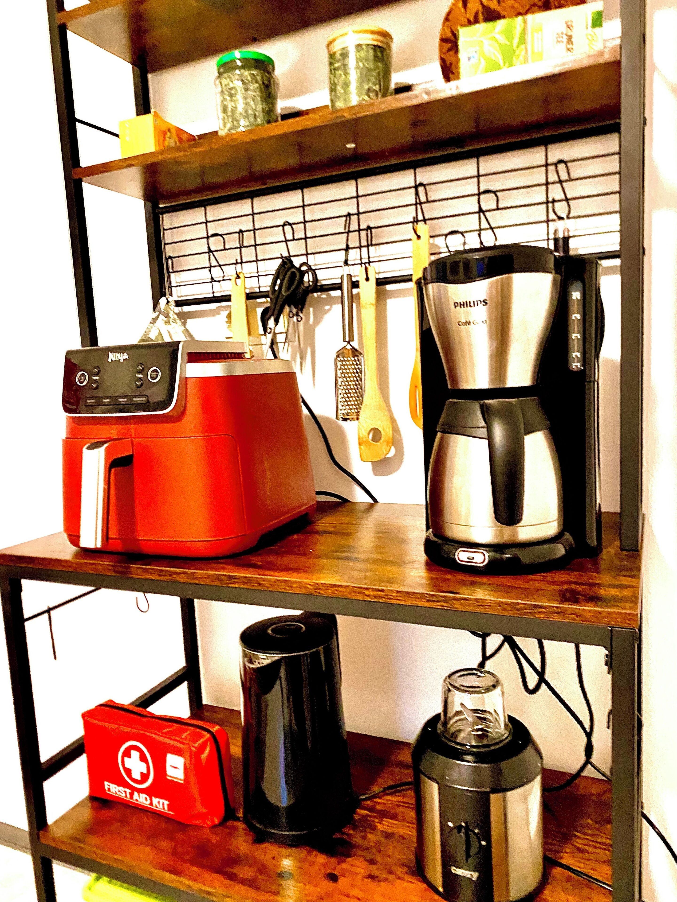 Eine Küche mit einer Kaffeemaschine, einem roten Gerät und einer Erste-Hilfe-Ausrüstung auf der Arbeitsplatte.