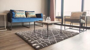 A modern living room with a blue sofa, two patterned pillows, a small table, and a patterned rug.