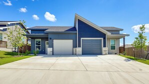Ein modernes, zweistöckiges Haus mit Garage, überdachter Auffahrt und gepflegtem Rasen.