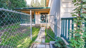 Ein Haus mit Veranda, einem Weg zum Eingang und einem Zaun aus Maschendraht.