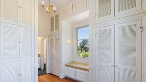 Un vestidor amplio con varias puertas, un banco y una ventana con vistas a la vegetación.
